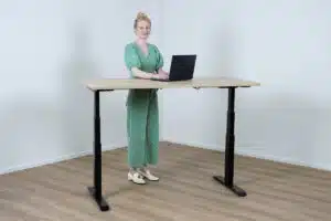Vrouw in groen pak staat achter haar sta bureau.
