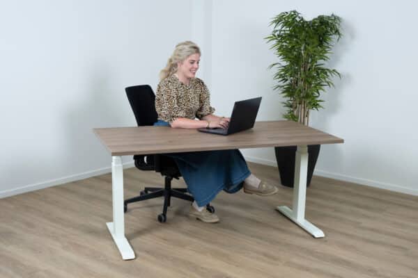 Vrouw zit achter een sta bureau met haar laptop.