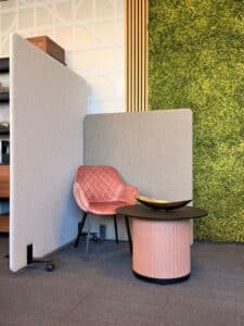 Beige en grijze akoestische scheidingswand naast roze stoel.