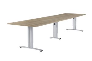 Witte achtergrond met daarop een vergadertafel. Deze vergadertafel is rechthoekig, met drie aluminium poten eronder. Het blad is licht eiken.