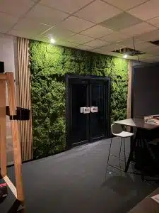 Kantoorruimte met een moswand om de deur heen.