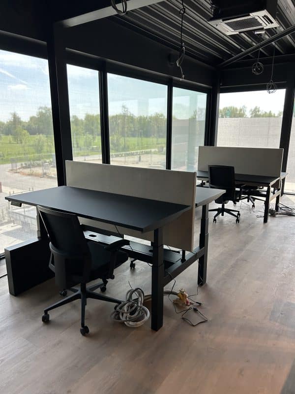 Zwart duo bureau met grijs akoestisch paneel.