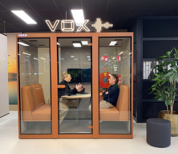 Roze vergadercabine met twee roze treinbanken en mensen erin die overleggen.