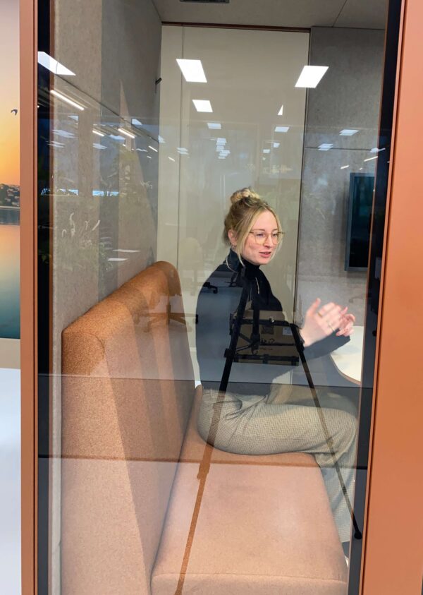 Detailshot van vrouw in roze overlegcabine die zit op een roze treinbank.