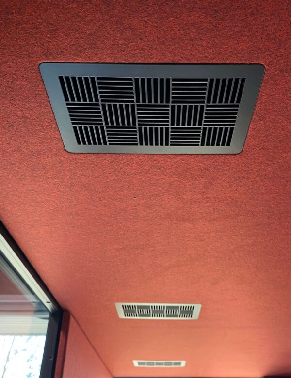 Zwarte ventilatieroosters in rode vergadercabine.