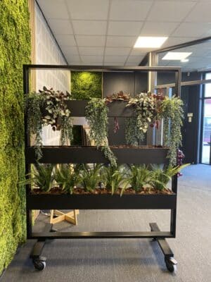 Kantooromgeving met grijze vloertegels en links een moswand. En we zien een roomdivider met wielen en drie rijen plantenbakken. Dit is het model De Heuning.