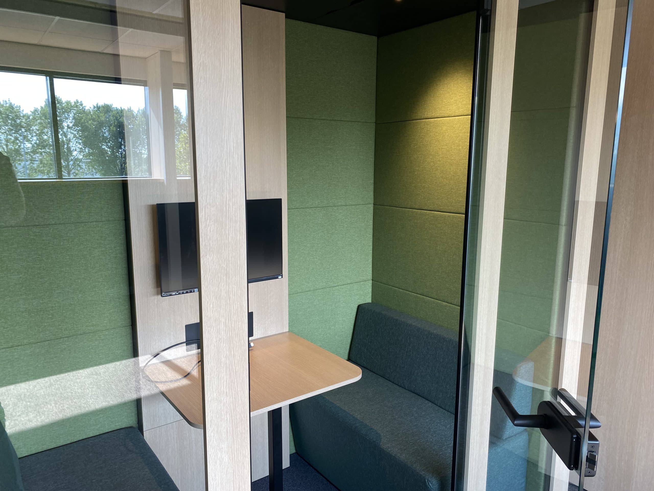 interieur van een akoestische cabine met groene bekleding en een tafeltje