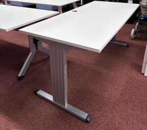Gebruikt bureau 160x80cm met een aluminium onderstel en een wit blad, in een ruimte met rode vloerbedekking.