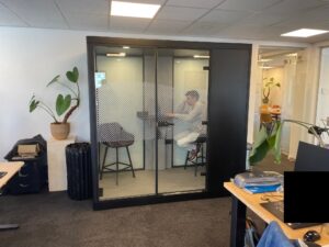 Zwarte grote geluidsdichte cabine met twee werkplekken erin.