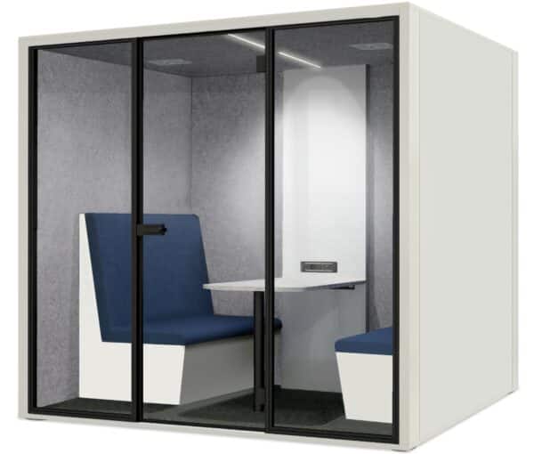 Witte achtergrond met daarvoor een akoestische overlegplek met witte wanden. De binnenkant is lichtgrijs en er staan twee treinbanken met een tafel ertussen. Dit is de geluidsdichte cabine 4 personen Model PK3.
