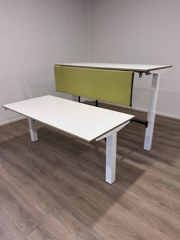 Elektrisch verstelbaar bureau met witte poten en bladen en een groen akoestisch scherm.