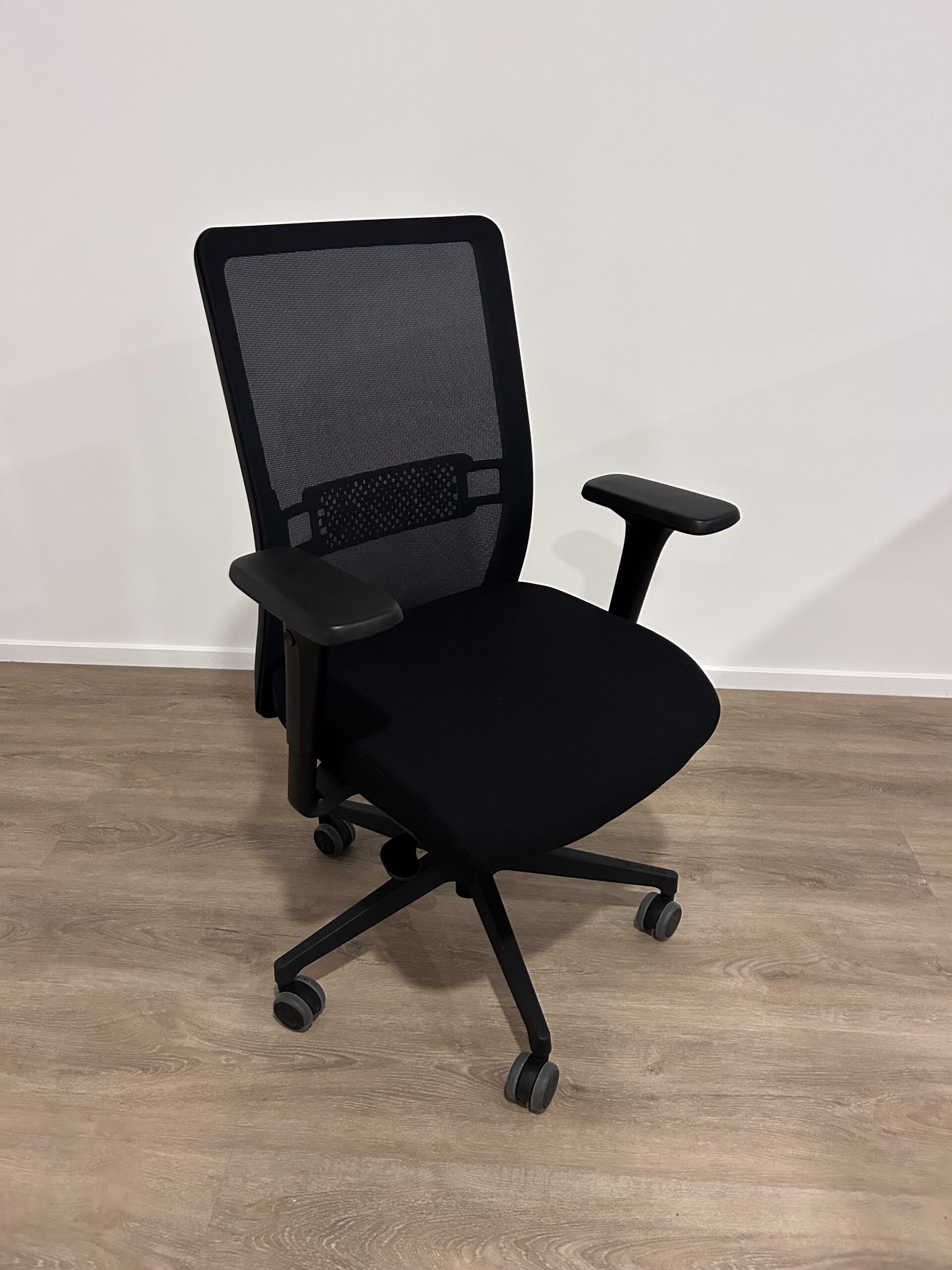 Zwarte bureaustoel met netweave rug en gestoffeerde zitting.