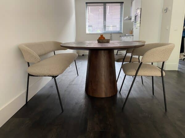 Gebruikte eetkamerset met een donkerhouten tafel, een zandkleurige eetkamerbank links en twee eetkamerstoelen in dezelfde kleur rechts.