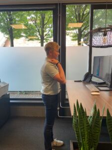 Jongen raakt schouder aan terwijl hij achter sta bureau staat. 