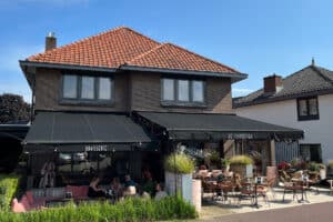 Restaurant de IJsboetiek met zwarte terrasschermen. 