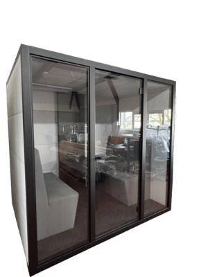 Tweedehands geluidsdichte cabine met een lichtgrijze zijkant en zwart frame aan de voorkant.