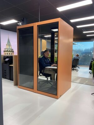 Roze akoestische werkplek met bureaustoel en bureau en persoon erin.