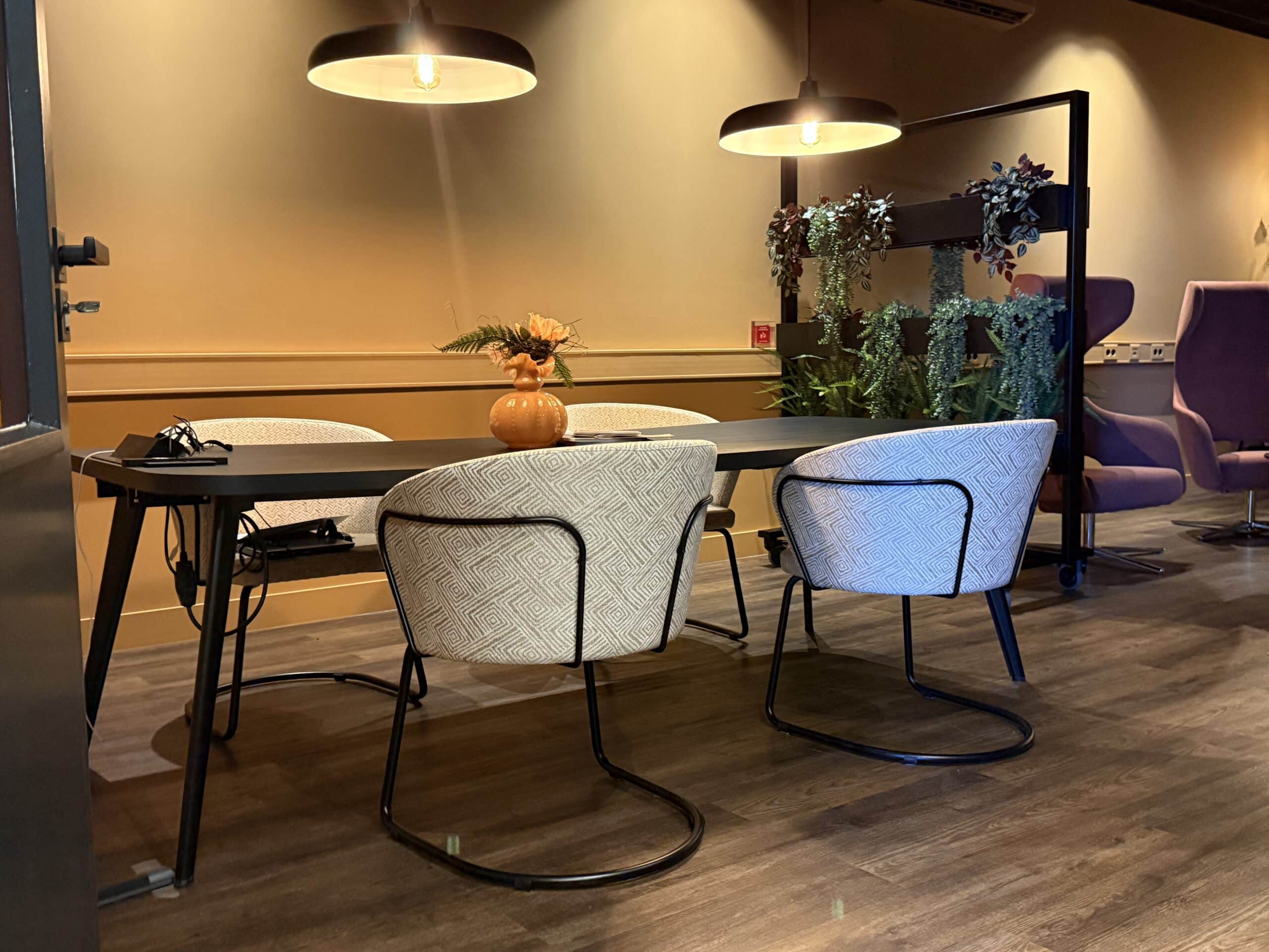 Vergaderruimte met zwarte vergadertafel en zandkleurige stoelen.