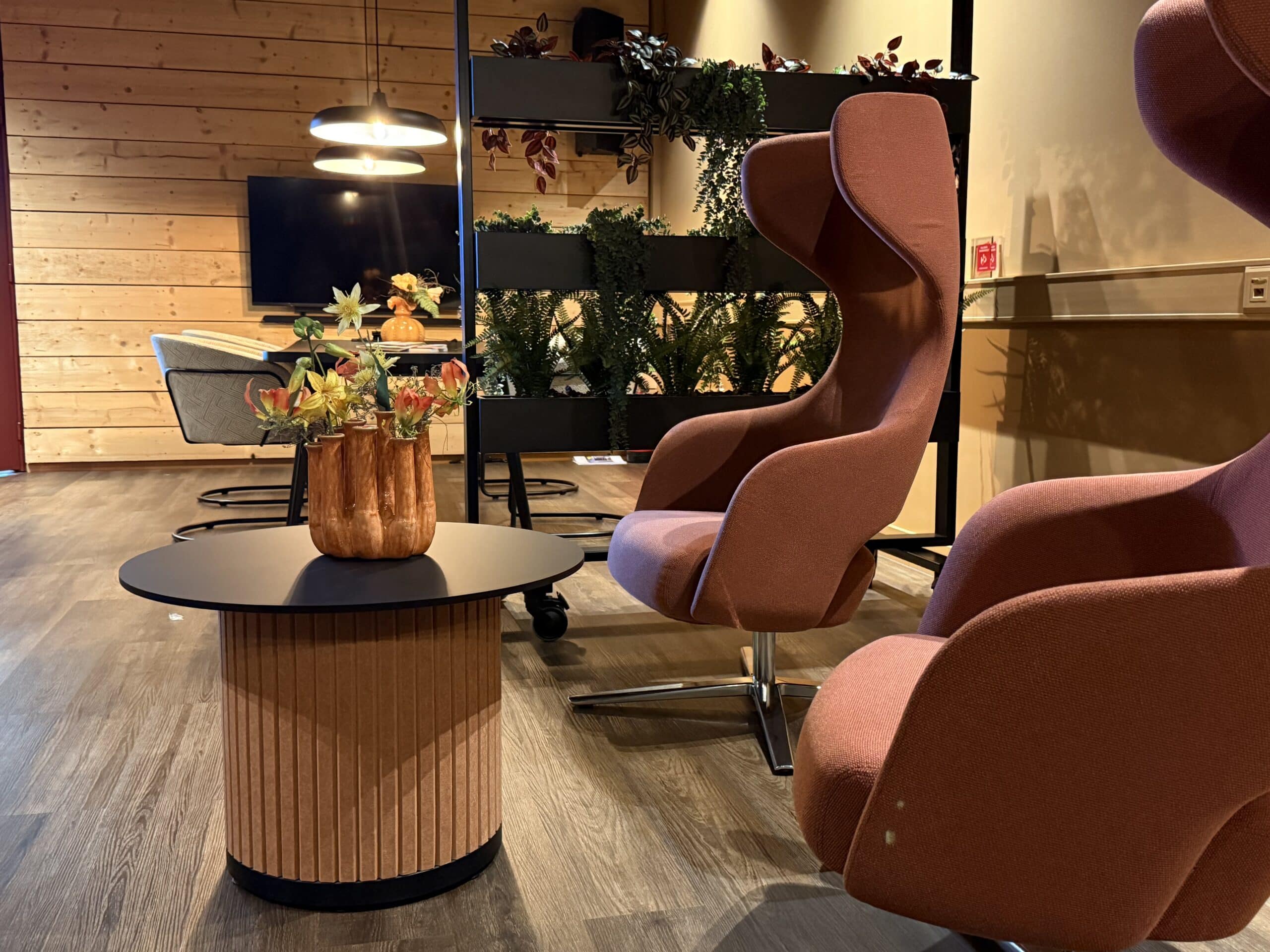 Rode vergaderstoelen met vilten salontafel.