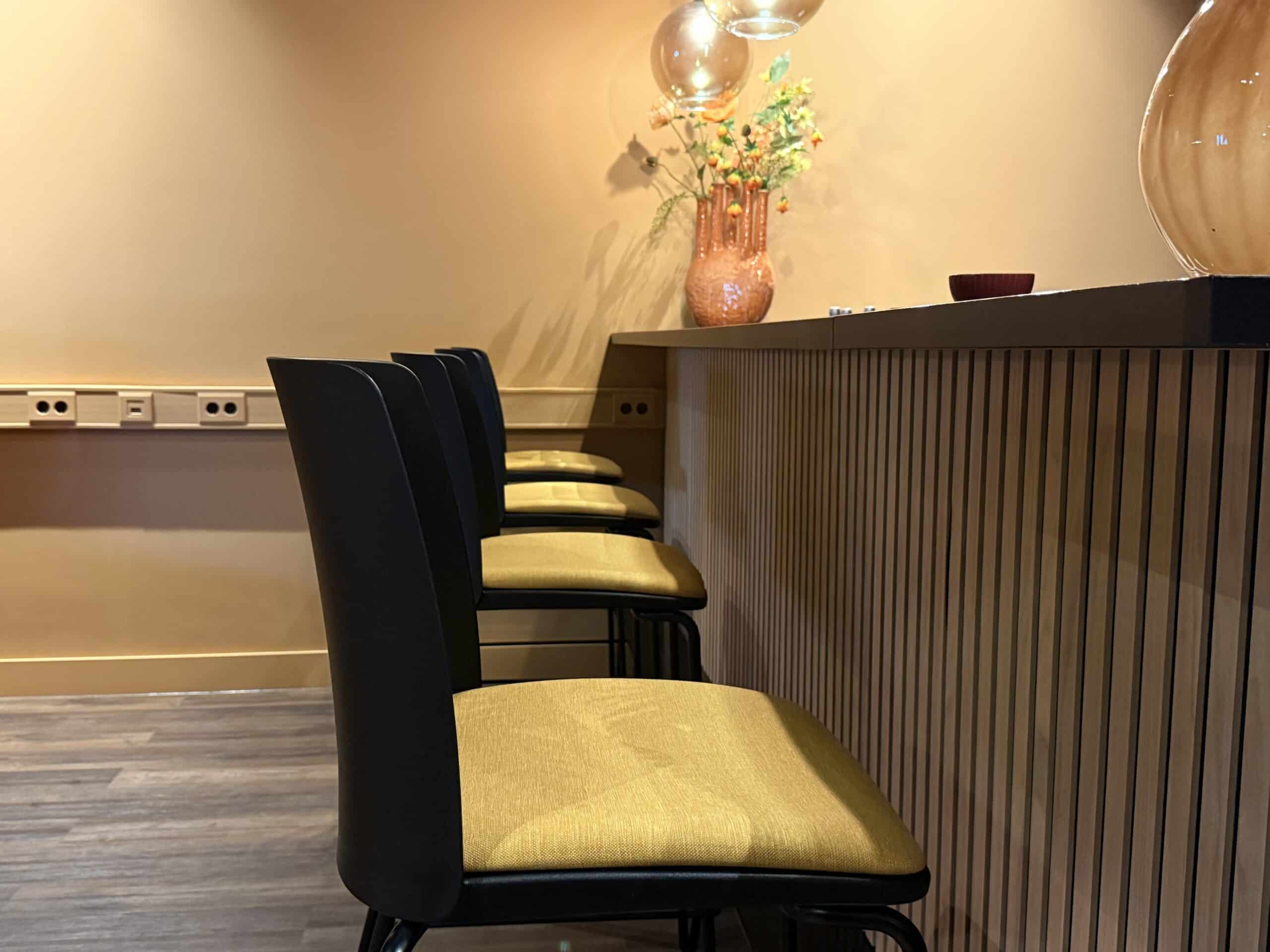 Gele barstoelen achter bar.