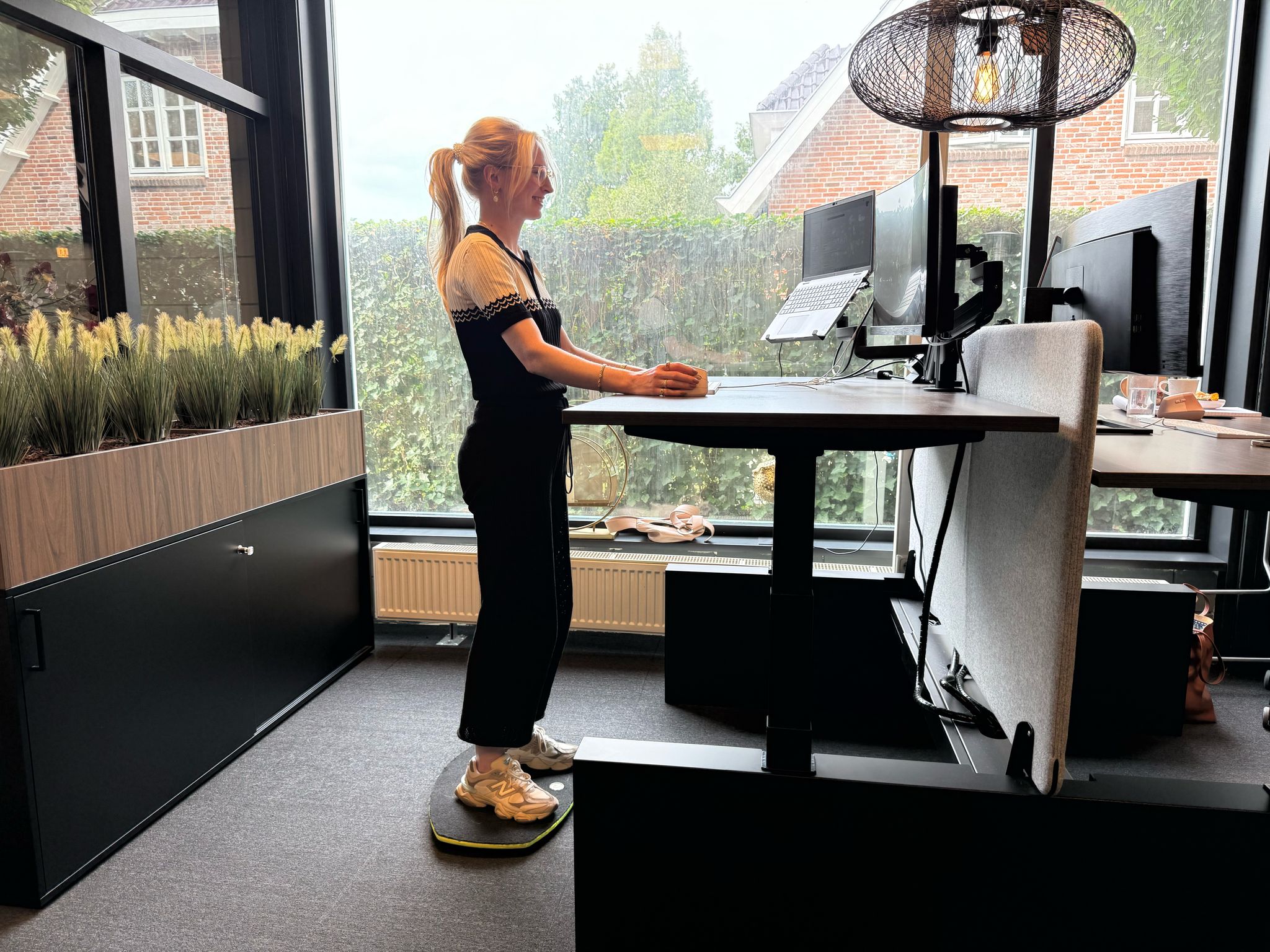 Vrouw achter een bureau met een rustige, opgeruimde indeling.