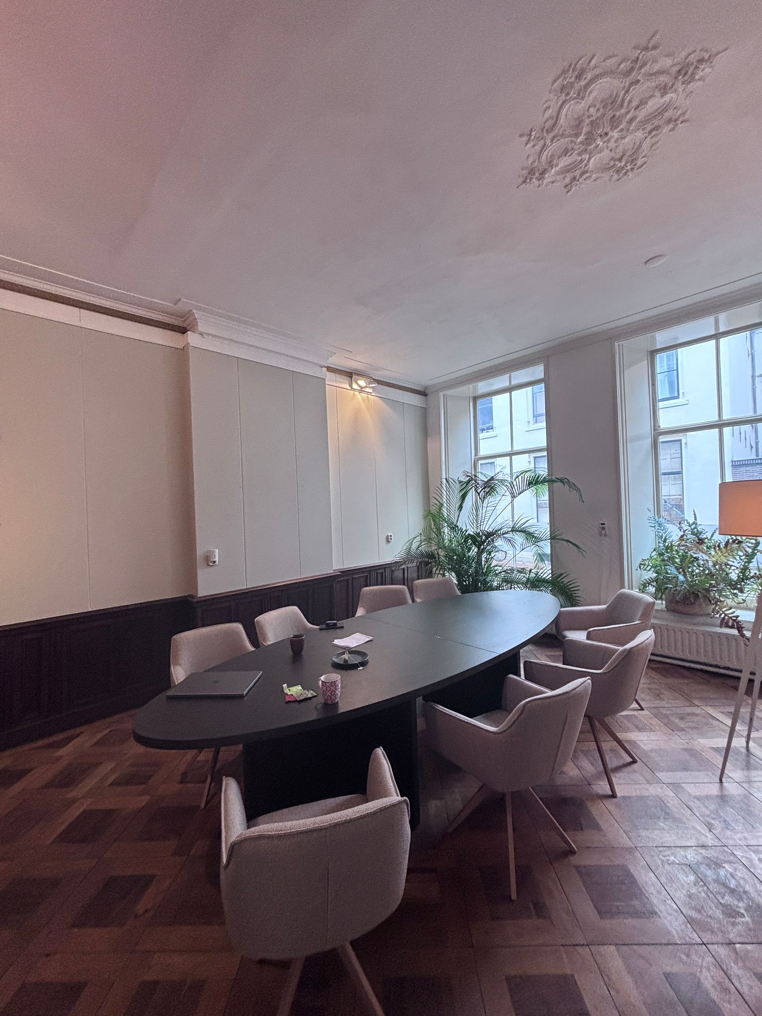 Ruimte met ovalen vergadertafel en vierpoots stoelen.