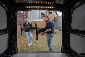 Joan en Casper tillen een bureau in de bus.