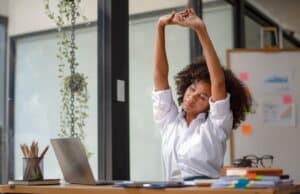 uitrekkende dame achter bureau gezond werken op kantoor