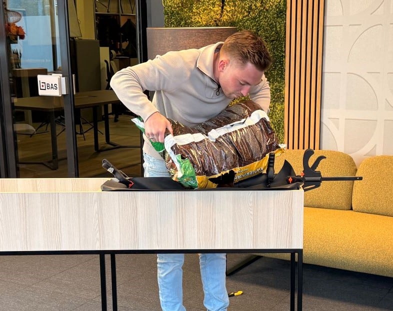 Joan doet kamerplantgrond in de plantenbak.