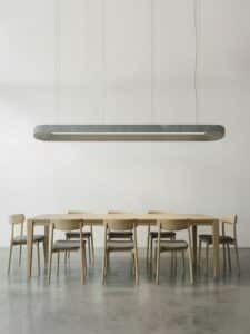 Minimalistische vergadertafel en stoelen onder akoestische lamp