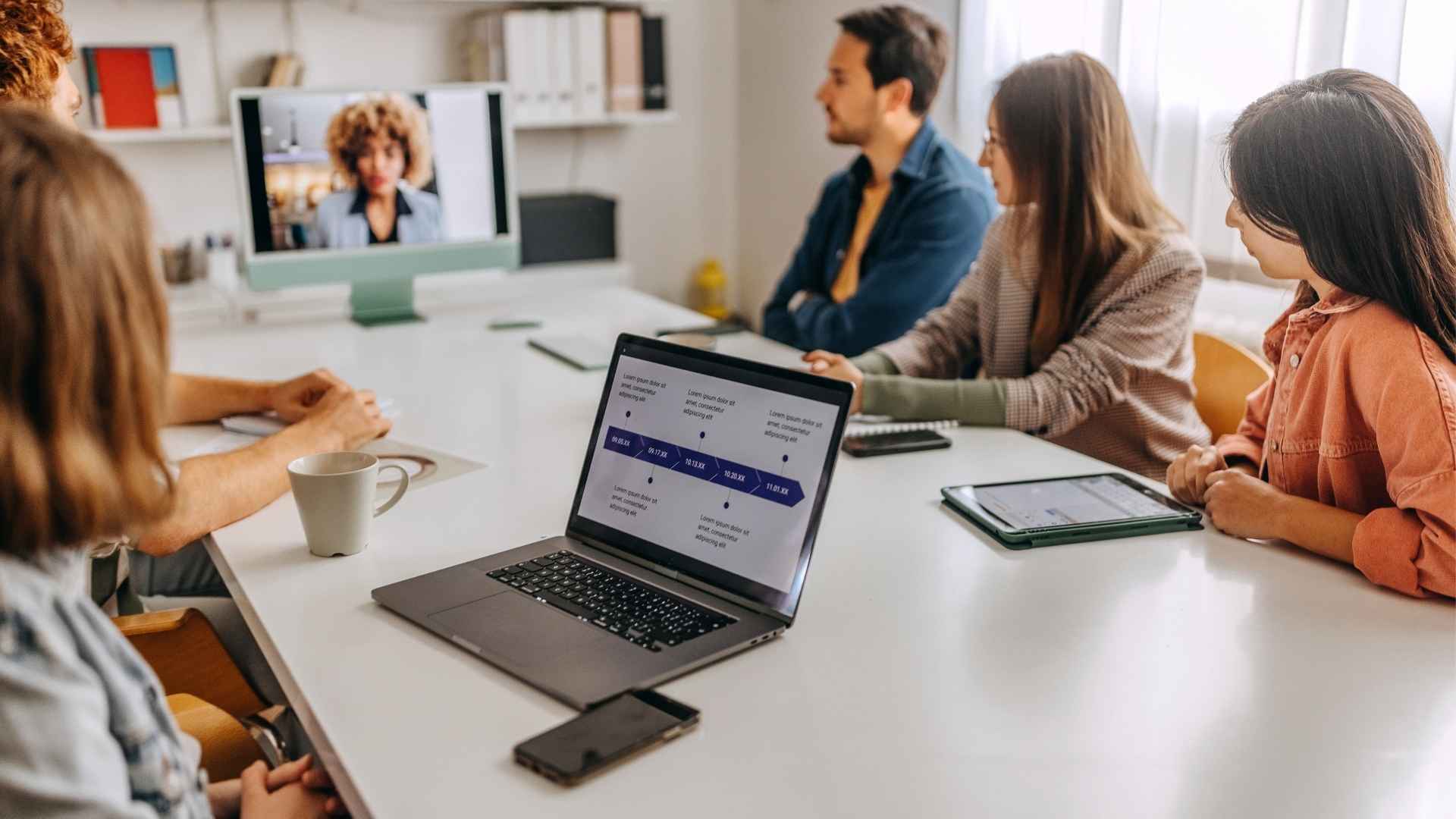 Hybride vergaderen setting met mensen aan tafel en op het scherm