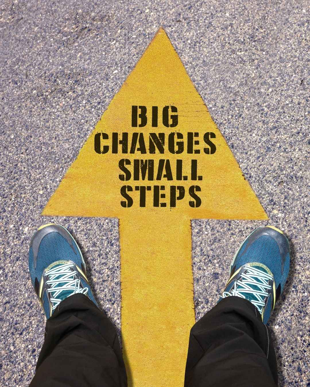 Gele pijl op asfalt met tekst Big changes, Small steps