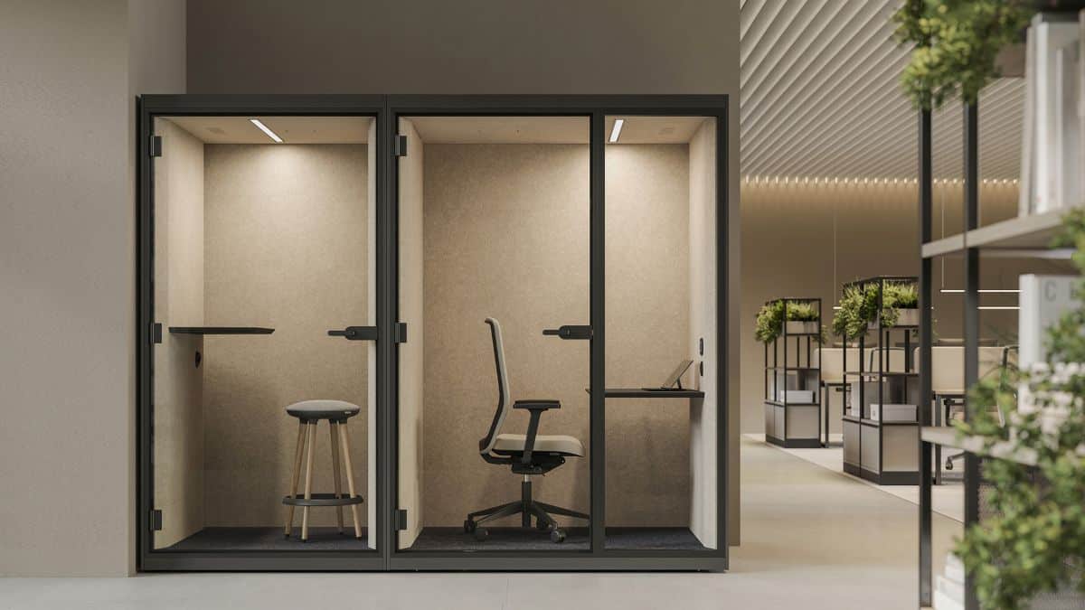Werkcabine met een bureaustoel, tafel en zandkleurige bekleding van de wanden.