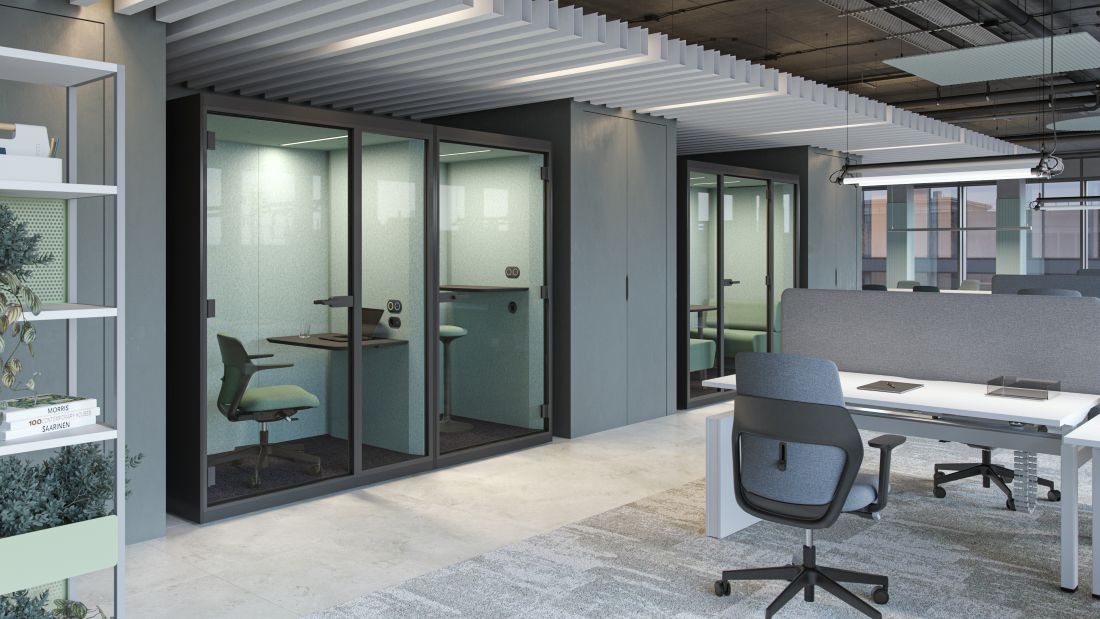 Groene werkcabine met bureaustoel en tafel.
